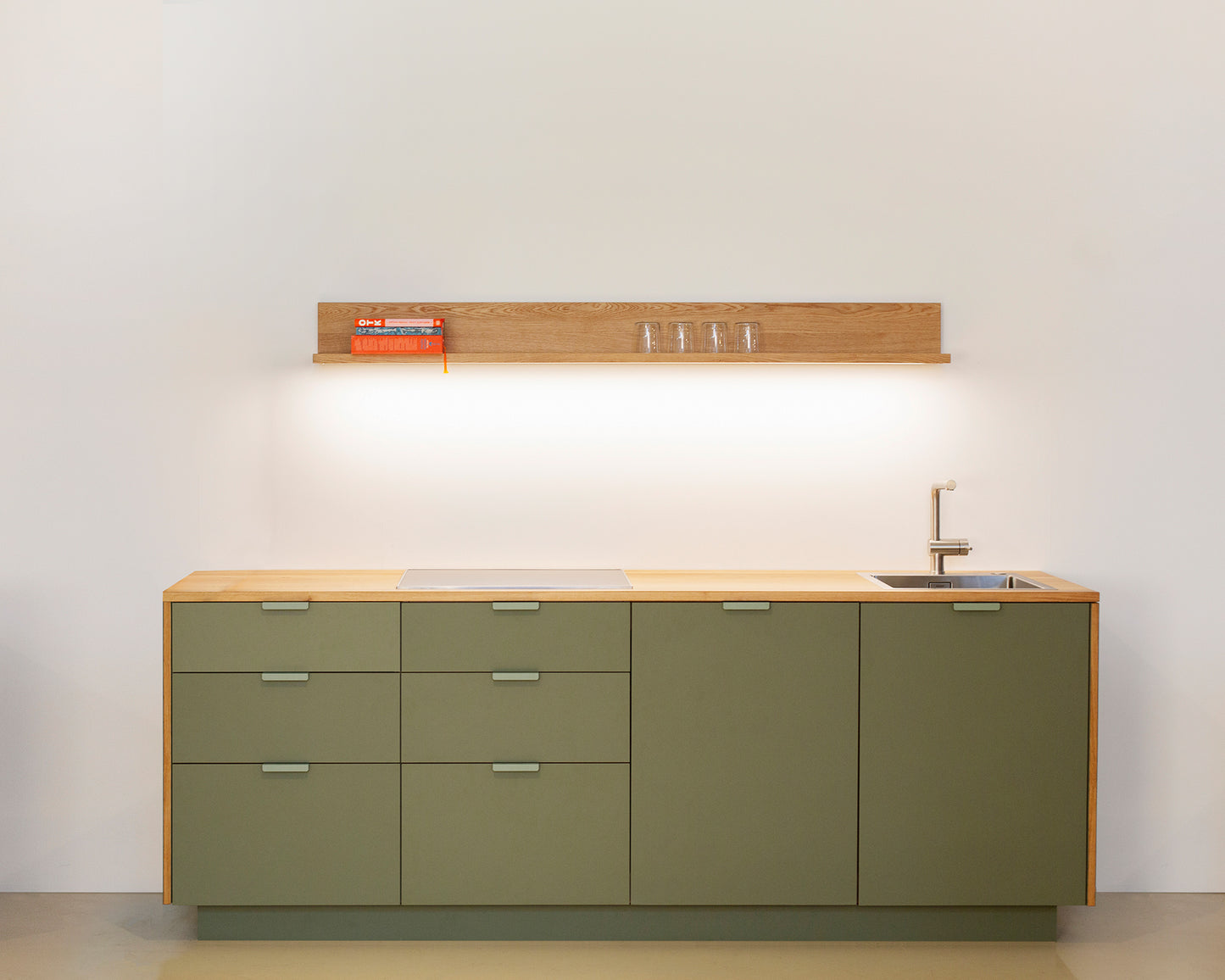 Compact kitchen unit with modular design, featuring sleek green cabinets, wooden countertop, and integrated appliances.