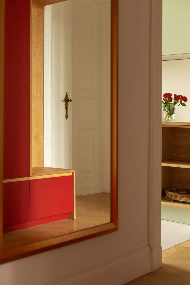 Blick in den Spiegel. rote Linoleumgarderobe und grüne Küche 
