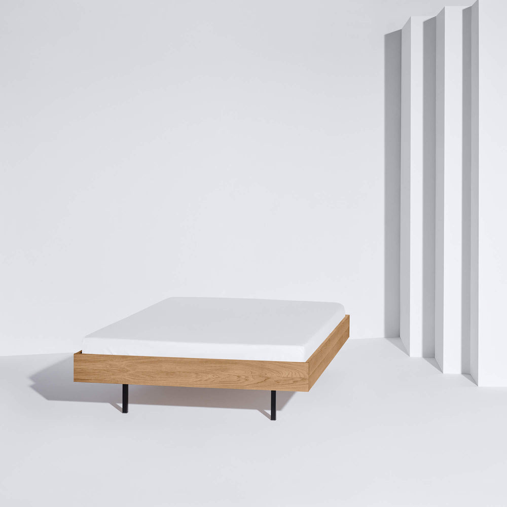 Das Unidorm Bett Eiche in der schlichten Version ohne Bettbezug in einem weißen Raum